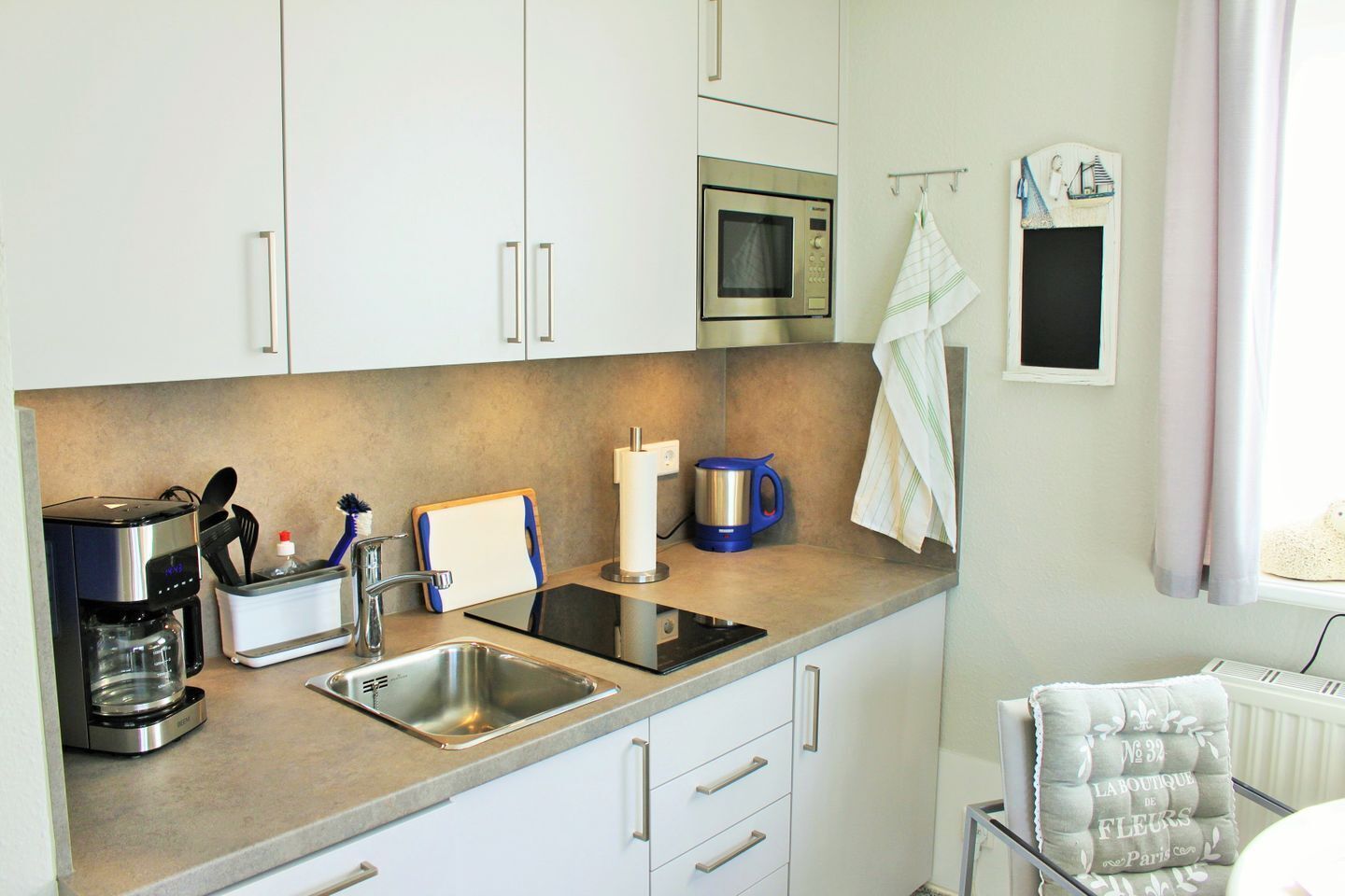 Een moderne keuken met een koffiezetapparaat, waterkoker en magnetron.