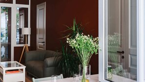 Un interior moderno con una mesa de comedor, sillas, un jarrón con flores y un ventanal grande.