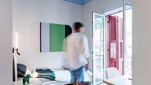 Una habitación con cama, escritorio, silla, lámpara colgante y puerta corredera de vidrio.