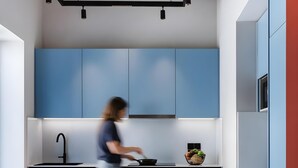 Una cocina moderna con armarios azules, una isla central y una persona cocinando.