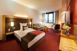 A hotel room with a large bed, a sofa, a desk, and a TV. - Sunday am Main Taunus Zentrum Frankfurt/Sulzbach Single Room (Sulzbach (Taunus))