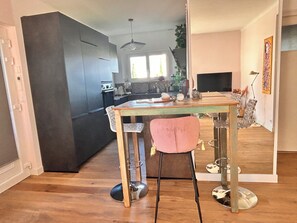 Eine moderne Küche mit dunklen Schränken, einem Holztisch und einem pinken Stuhl.