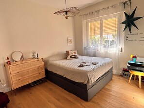 A bedroom with a bed, dresser, and a window with blinds. - The Good Life… (Fréjus)