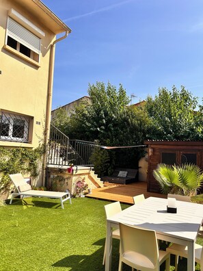Eine Terrasse mit Tisch und Stühlen, ein kleiner Garten und eine Holzterrasse.