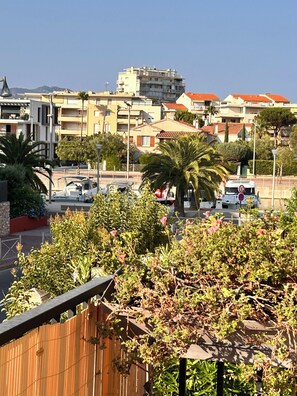 Una zona residencial con varios edificios, incluyendo un complejo de apartamentos de varios pisos y casas unifamiliares. Palmeras y arbustos diversos en primer plano.