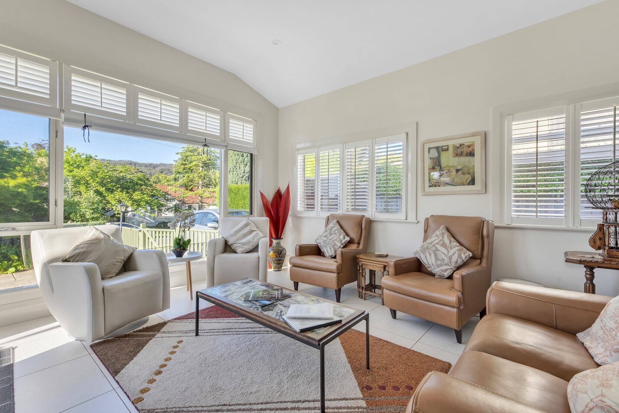 A spacious living room with a large window, a coffee table, and leather sofas.