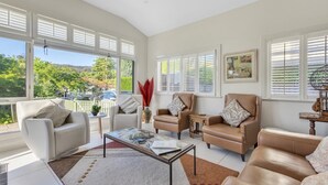 Ein geräumiges Wohnzimmer mit großem Fenster, einem Couchtisch und Ledersofas.