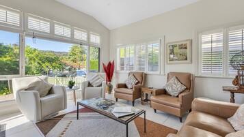 A spacious living room with a large window, a coffee table, and leather sofas.