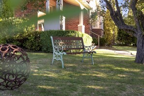 A bench in a well-maintained garden area with a brick building in the background.
