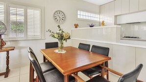 Ein Esszimmer mit Holztisch und -stühlen, einer Blumenvase und einer Uhr an der Wand.