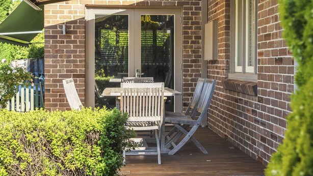 Eine Terrasse mit Tisch und Stühlen, ein Holzdeck und eine Backsteinmauer.