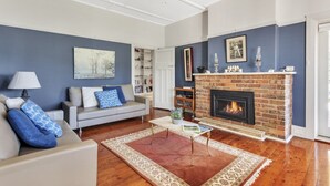 Ein Wohnzimmer mit Kamin, einer Couch, einem Couchtisch und einem Bücherregal.