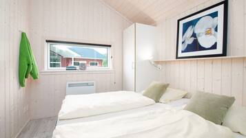 Ein Zimmer mit einem Bett, einem Fenster, einer Heizung und einem gerahmten Bild an der Wand.