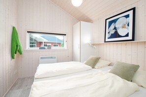Ein Zimmer mit einem Bett, einem Fenster, einer Heizung und einem gerahmten Bild an der Wand.