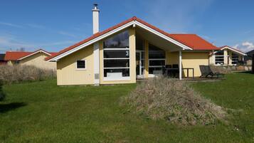 Ein einstöckiges Haus mit rotem Ziegeldach, Schornstein und einem großen Fenster.