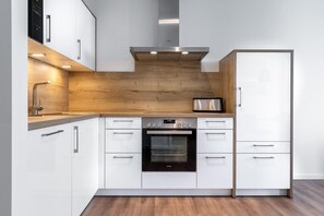 Eine moderne Küche mit weißen Schränken, einem eingebauten Backofen und einer Edelstahl-Dunstabzugshaube.
