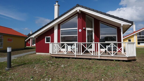 Et rødt etplanshus med en hvid balkon og skorsten.