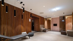 Um lobby de hotel moderno com uma parede de ripas de madeira, uma mesa de recepção, área de estar e uma sala de spa.