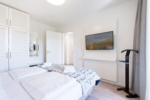 A hotel room with a bed, a wardrobe, a television, and a standing lamp. - Rückzugsort mit Parkblick (Travemünde)
