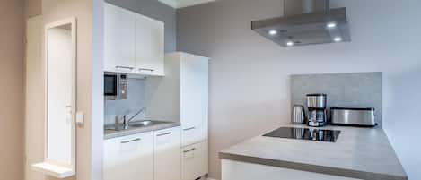 A modern kitchen with white cabinets, a microwave, a sink, and a coffee maker.