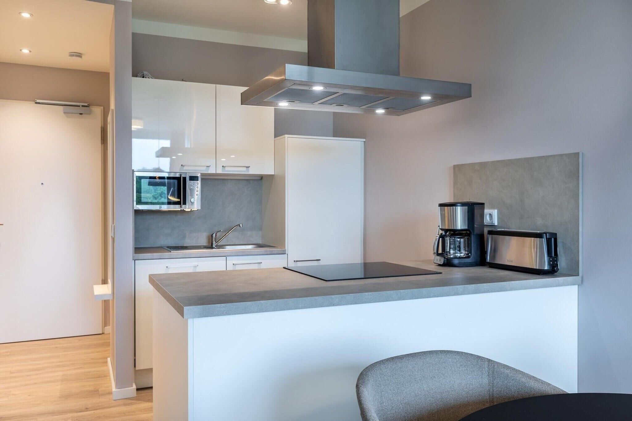 A modern kitchen with a built-in microwave, a coffee maker, and a sleek countertop.