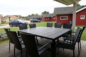 An outdoor patio with a rectangular table and eight chairs. - Hübsches Cottage mit Kamin (Großenbrode)