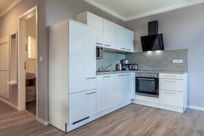 A modern kitchen with white cabinetry, a built-in oven, a microwave, and a coffee maker. - Apartment near the Baltic Sea (Travemünde)
