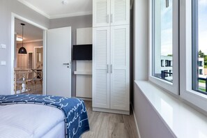 Un dormitorio con cama, armario, televisión y ventana con vistas.