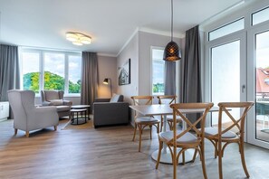 Una sala de estar moderna con sofá, sillas, una mesa de comedor y una lámpara colgante.