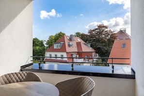 A balcony with a view of red-roofed buildings, a railing, and two chairs. - Apartment near the Baltic Sea (Travemünde)