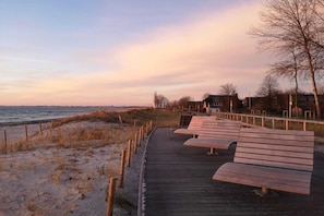 A wooden boardwalk leading to a beach with benches and a fence. - Charming Seaside Haven Oasis für 6 (Großenbrode)