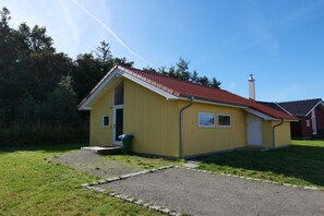 A yellow single-story building with a red-tiled roof, a chimney, and a small front porch. - Charming Seaside Haven Oasis für 6 (Großenbrode)