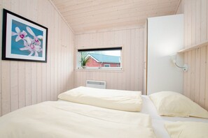 A room with two beds, a window with a view of a red building, and a framed picture of flowers. - Charming Seaside Haven Oasis für 6 (Großenbrode)