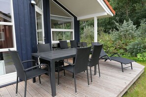 Eine Terrasse im Freien mit einem dunkelbraunen Tisch und Stühlen, umgeben von Pflanzen.