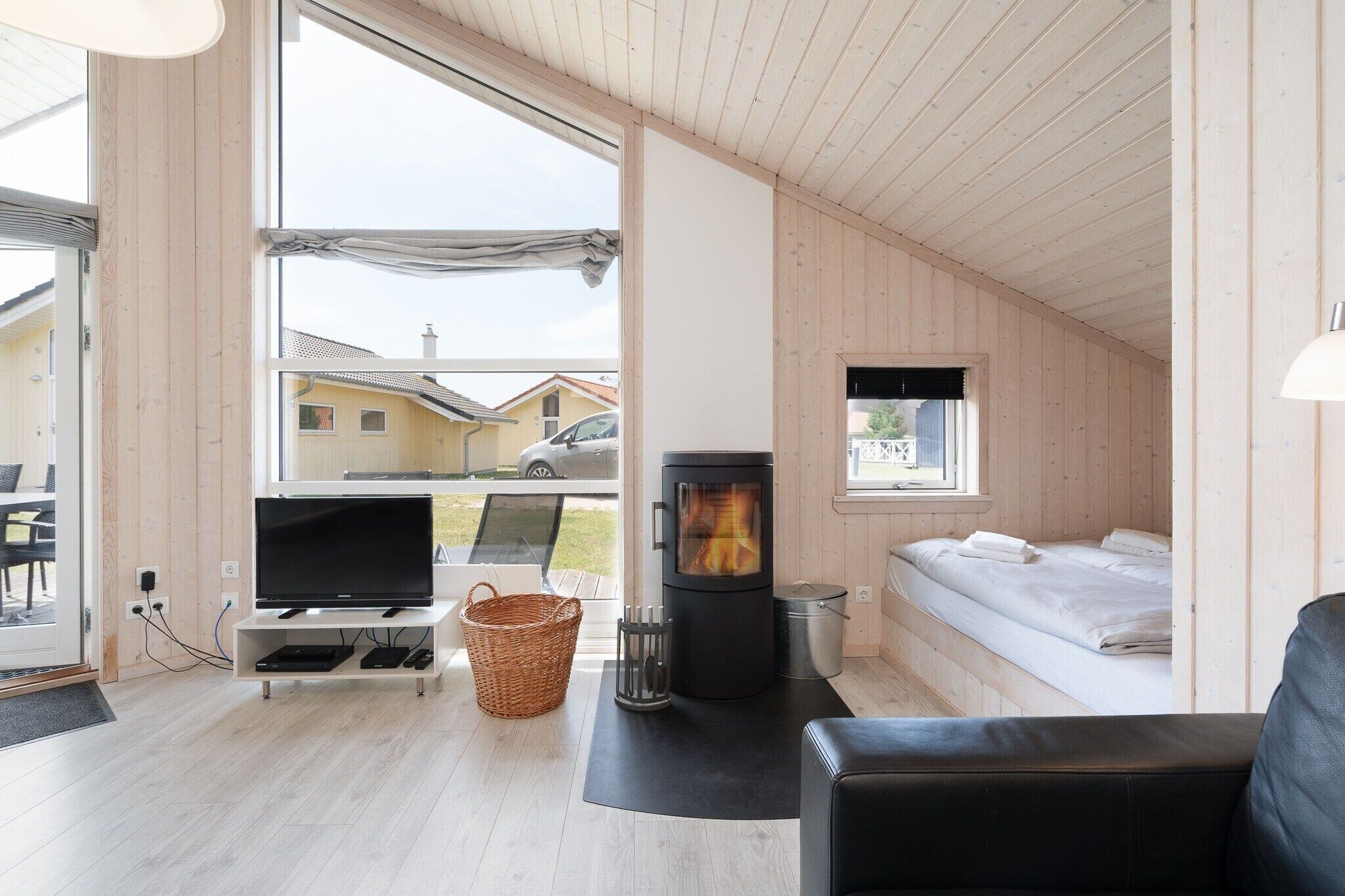 Une pièce confortable avec une télévision, une cheminée, un lit et une fenêtre donnant sur un quartier résidentiel.