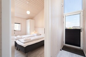 Ein Schlafzimmer mit zwei Betten, einem Fenster und einer zur Außenwelt führenden Tür.