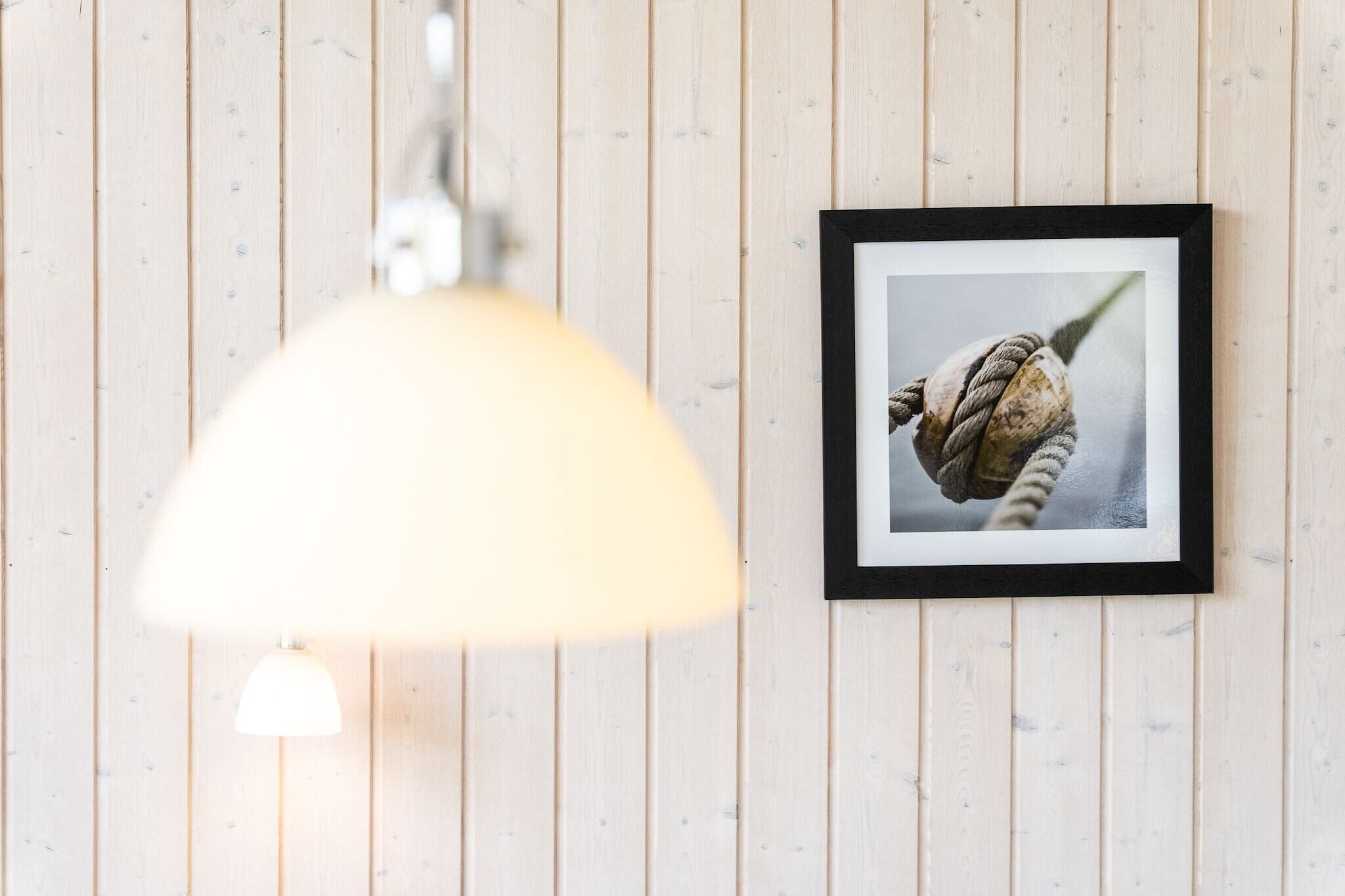 Een muur met een lijstfoto en een hanglamp.
