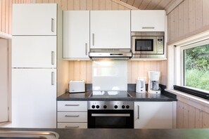 Une cuisine moderne avec des meubles blancs, un grille-pain Bosch, un four à micro-ondes Siemens et une machine à café Bosch.
