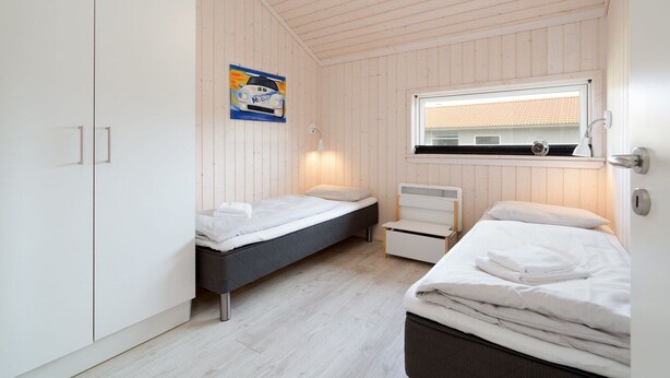 Ein Schlafzimmer mit zwei Betten, einem Kleiderschrank, einem Fenster mit Blick und einer Wandlampe.