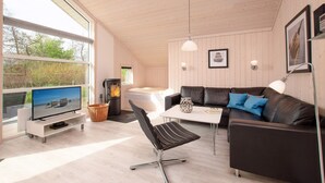 Ein modernes Wohnzimmer mit Fernseher, Ledersofa und Kamin.