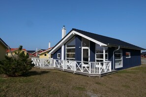 A single-story house with a dark blue exterior and white trim, featuring a balcony with a white railing. - Gemütliches baltisches Versteck für 6 (Großenbrode)