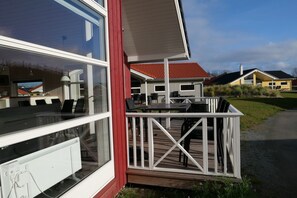 A modern building with large windows, a deck with outdoor furniture, and a red roof. - Nordische Flucht nahe der Ostsee (Großenbrode)