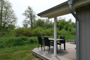 Un patio al aire libre con una mesa y sillas, rodeado de follaje y árboles.