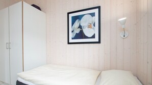 A bedroom with a bed, a wardrobe, and a framed picture on the wall. - Skandinavischer Rückzug für 6 (Großenbrode)
