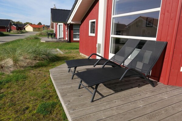 A red building with a wooden deck and two black lounge chairs. - 6-Gäste-Aufenthalt an der skandinavischen Küste (Großenbrode)