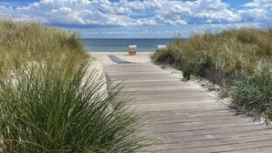 Una pasarela de madera que conduce a una playa flanqueada por dunas.