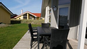 Un patio al aire libre con una mesa y sillas, una terraza de madera y un edificio con un cartel de número.