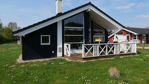 Moderni talo, jossa on suuri terassi, savupiippu ja tilava sisustus.