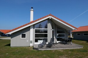 A modern house with a sloped roof, large windows, and a deck with outdoor furniture. - Nordischer Meereshafen in Großenbrode (Großenbrode)