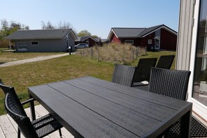 An outdoor patio with a table and chairs, a pathway leading to houses, and a clear sky. - Nordischer Meereshafen in Großenbrode (Großenbrode)